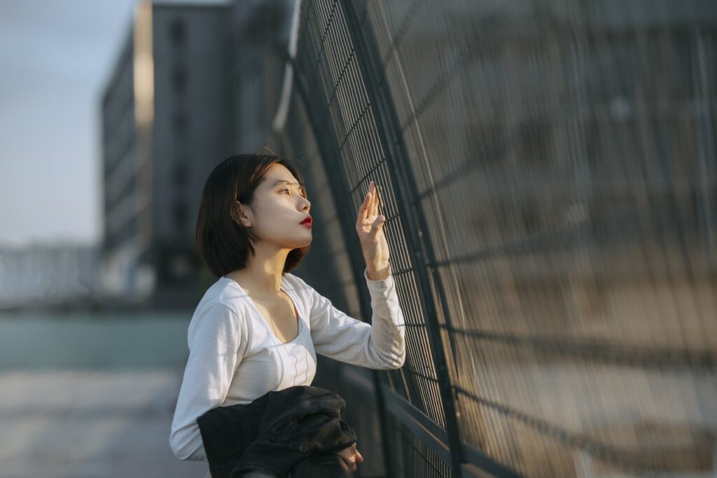 Woman with impostor syndrome looking through the fence