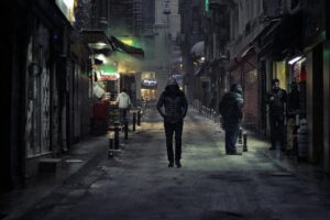 A man with impostor syndrome walking down a dark street